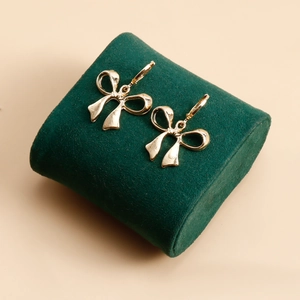 Détail macro de boucles d'oreilles nœud doré avec éclat métallique sur velours