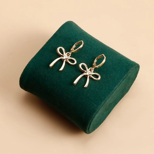 Vue macro de boucles d'oreilles nœud en métal doré sur coussin en velours vert foncé