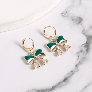 Detailed macro view of two-tone green and cream enamel bow-knot dangle earrings