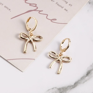 Gros plan de boucles d'oreilles nœud dorées sur un fond élégant en marbre