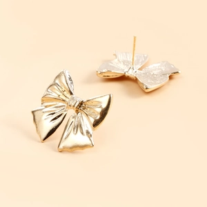 Detailed macro view of golden bow earrings featuring elegant silk-like metal textures