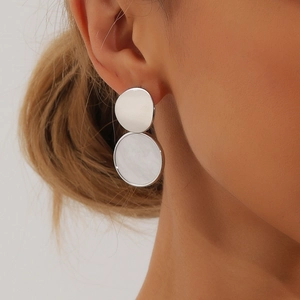 Gros plan d'une boucle d'oreille géométrique argentée avec nacre sur le mannequin