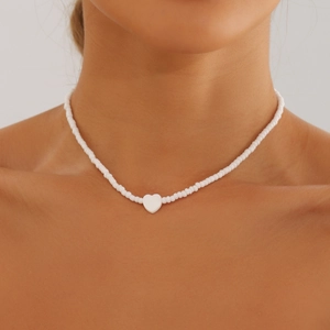 Dettaglio collana girocollo bohémien di perline bianche con ciondolo a cuore in madreperla