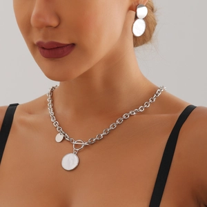 Détail d'un ensemble collier et boucles d'oreilles argentés avec nacre blanche et fermoir OT
