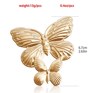 Dettaglio pendente a farfalla dorata con specifiche di misura 6,7 cm e peso di 13 g