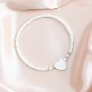 Dettaglio macro della collana di perle bianche con ciondolo a cuore in madreperla su seta