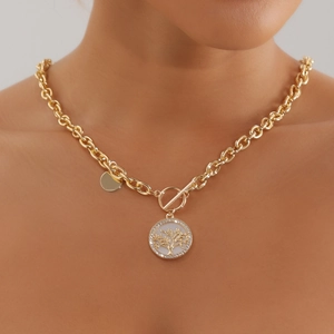 Close-up of gold chain necklace with life tree pendant and white shell inlay detail