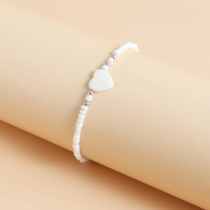 Dettaglio della collana di perline bianche con pendente a cuore in madreperla su supporto