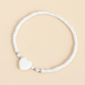 Dettaglio della collana bohémien di perline bianche con ciondolo a cuore in madreperla