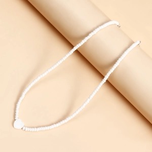 Dettaglio della collana di perline bianche con ciondolo a cuore in madreperla e gancio