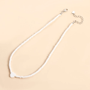 Dettaglio della collana bohémien di perline bianche con ciondolo a cuore e chiusura a moschettone