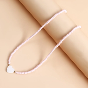 Dettaglio della collana di perle rosa con pendente a cuore bianco e tocchi dorati