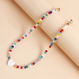 Dettaglio di collana di perle sfaccettate colorate con un ciondolo a cuore in madreperla