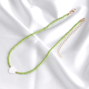 Dettaglio della collana bohémien di perline verdi con ciondolo a cuore e chiusura oro