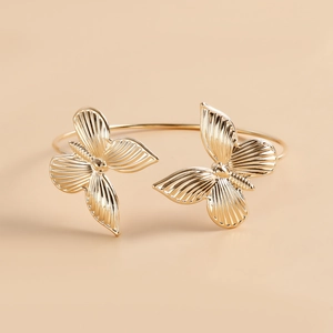 Dettaglio macro di un bracciale a polsino con farfalla dorata e trame alari intricate