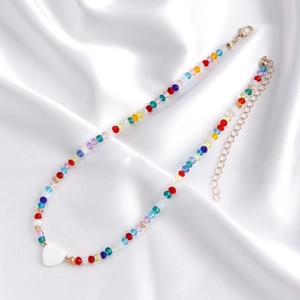 Dettaglio della collana di perline colorate con ciondolo a cuore bianco su seta bianca