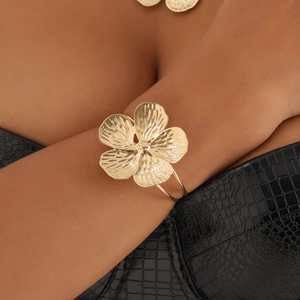 Detalle de brazalete de flor dorada con texturas de vetas en la muñeca