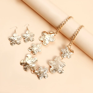 Detailaufnahme des goldenen Blumen-Schmucksets mit gehämmerter Metalloberfläche