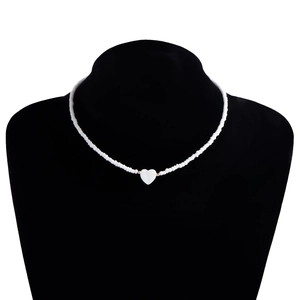 Dettaglio di collana con perline bianche e ciondolo centrale a forma di cuore in madreperla