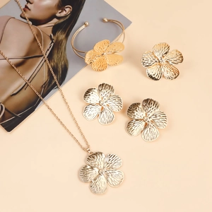 Vista de conjunto de joyas con flores doradas que incluye collares y pulsera sobre beige