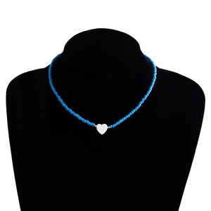 Dettaglio della collana di perline blu con ciondolo a cuore bianco su un supporto