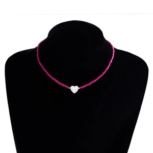 Dettaglio della collana di perline fucsia con pendente a cuore bianco su espositore