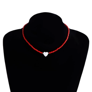 Dettaglio della collana fatta a mano con perline rosse e ciondolo a cuore bianco su busto nero