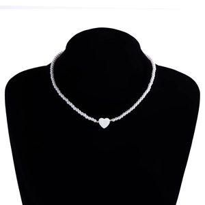 Dettaglio di una collana di perle con ciondolo a cuore su un espositore per gioielli nero