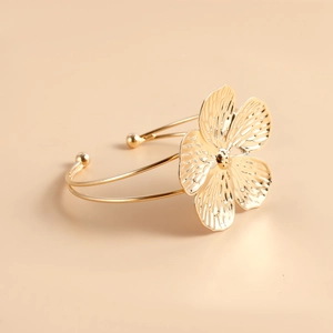 Primer plano del brazalete de flor dorada con pétalos texturizados y diseño de aro abierto
