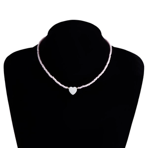 Dettaglio collana di perline rosa con ciondolo a cuore in madreperla bianca su busto nero
