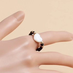 Dettaglio dell'anello di perline nere con ciondolo a cuore bianco su una mano
