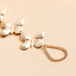 Détail macro de maillons papillons dorés avec textures d'ailes sur ce bijou chic
