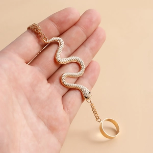 Détail de la gourmette serpent dorée avec écailles ciselées et strass noirs aux yeux