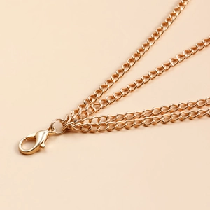 Detailopname van meerlaagse gouden enkelband met karabijnsluiting en fijne schakelketting