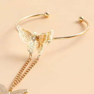 Détail du bracelet papillon ajouré doré avec strass scintillants et chaînes pendantes