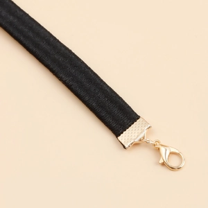 Detailansicht der schwarzen elastischen Beinkette mit hochwertigem goldnem Karabinerverschluss