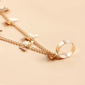 Détail de la bague dorée réglable et du pendentif papillon sur le bracelet de doigt