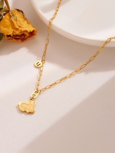 Detailopname van gouden konijn-ketting met luck-gravure op witte keramische schaal