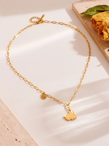 Macro-opname van gouden konijnenketting met luck-hanger en schaduwen op steen