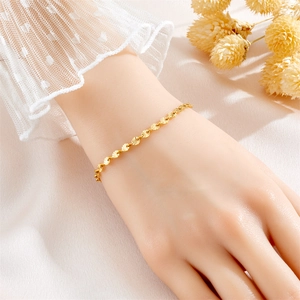 Close-up of gold titanium clover bracelet on wrist with elegant lace cuff and dried flowers