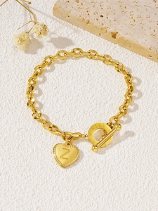 Detail van gouden hartvormige hanger met letter Z en OT-sluiting op een schakelarmband