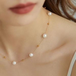 Elegant French style pearl and gold bead titanium steel necklace on a female model neck