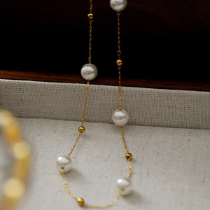 Elegant gold titanium steel necklace featuring white pearls and gold bead accents