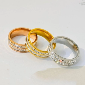 Detailed view of gold, rose gold, and silver rings with double row of clear zircon stones