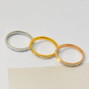 Macro detail of three slim stackable rings in silver, gold, and rose gold with pavé crystals