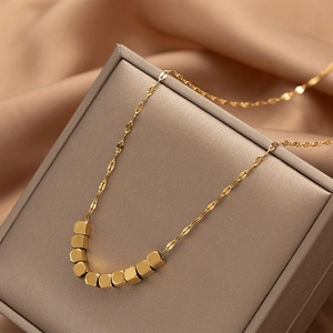 Close-up of a gold geometric block pendant necklace on a premium silk fabric display