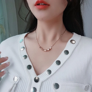 Rose gold titanium necklace with seven geometric cube pendants on a model's collarbone