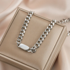 Silver Cuban link necklace featuring a polished oval plaque charm on a silk jewelry box