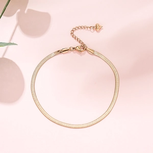 Bracelet de cheville élégant chaîne serpent dorée avec pendentif cœur sur fond rose