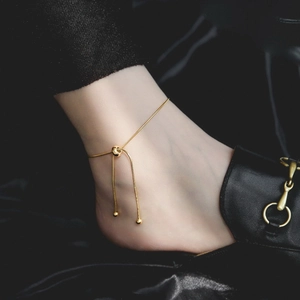 Detail of adjustable gold snake chain anklet with sliding bead on female model